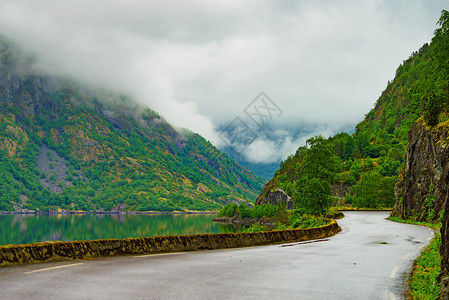 挪威景观诺威霍达尔兰沿峡湾的老路雾蒙蒙的雨天挪威峡湾Eidfjorden的老路背景