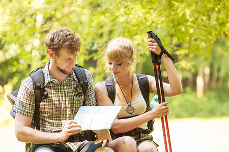 男女游客背包客休息时阅读森林旅行两个徒步旅行者寻找方向指南背包旅行暑假冒险背景图片