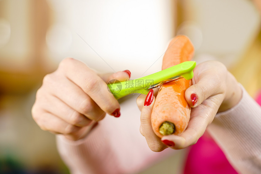女人用食物剥皮机剥蔬菜烹饪女上菜前先准备胡萝卜图片