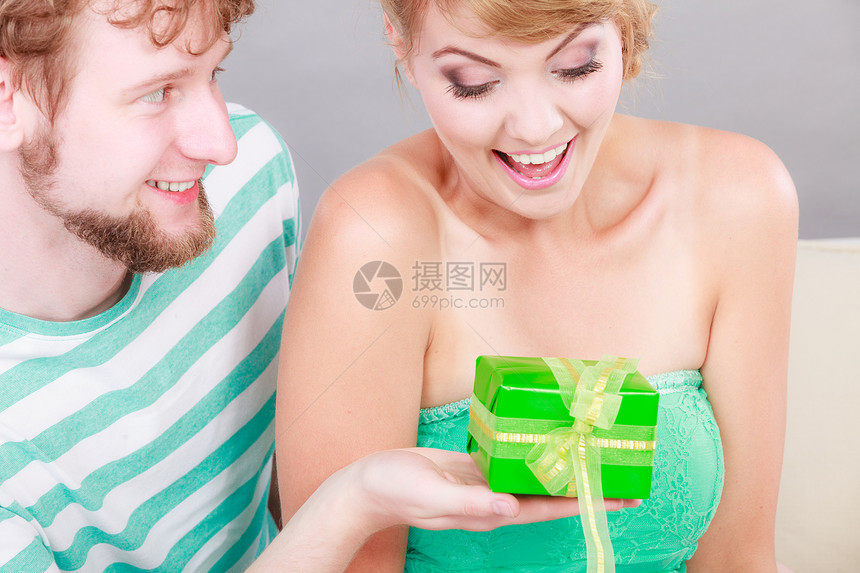夫妇坐家里的沙发上轻人给女人礼物盒图片