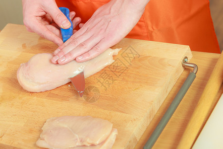 食物准备,烹饪男手厨师切生鸡肉胸木板上高清图片