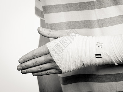 骨折脱位的部分身体男用手包扎帮助的药物治疗轻人疼痛的手掌手臂部分身体男子用绷带的手背景图片