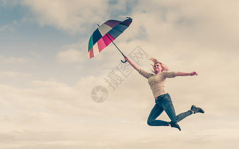 飞伞快乐,享受天气,感觉很棒的女人用五颜六色的伞跳进清澈的蓝天女人海滩上着五颜六色的雨伞跳跃背景