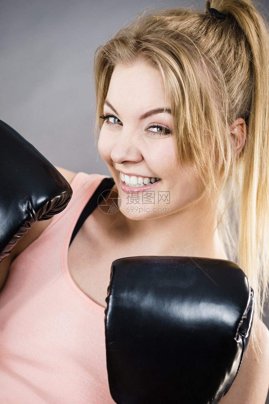运动的女人戴着红色的拳击手套,打架工作室灰色背景上拍摄戴拳击手套的快乐微笑的女人图片