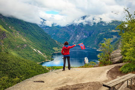 施韦弗利格Flydalsjuvet角度欣赏峡湾Geirangerfjorden风景的女游客,举着挪威巡航度假旅行吉兰格峡背景