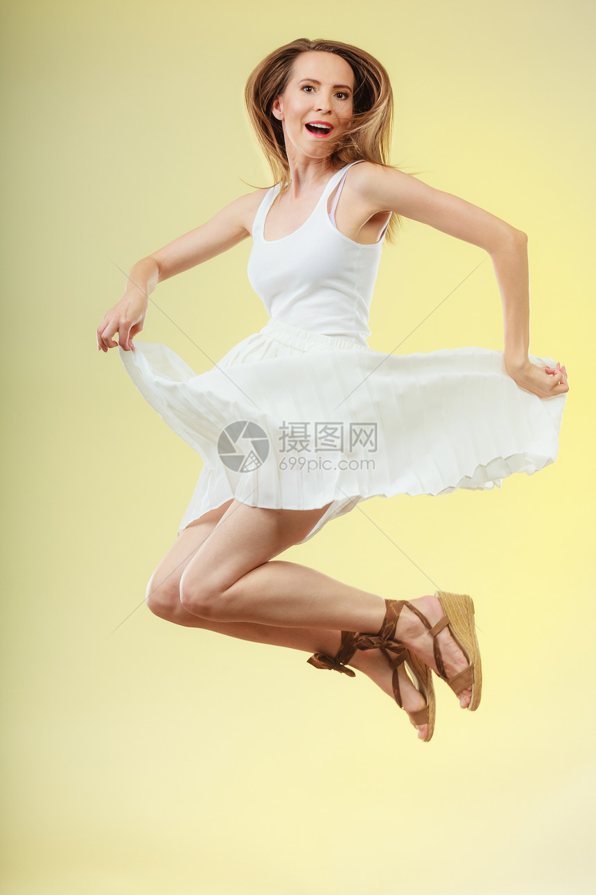 假期,夏天幸福穿着白色连衣裙的女人跳着女模特全长黄色背景图片