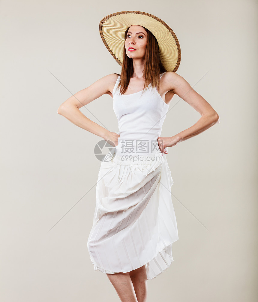 假日夏季时尚女人戴着大草帽白色连衣裙女模特摆明亮的灰色背景上图片