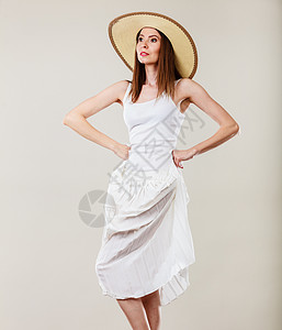 假日夏季时尚女人戴着大草帽白色连衣裙女模特摆明亮的灰色背景上图片