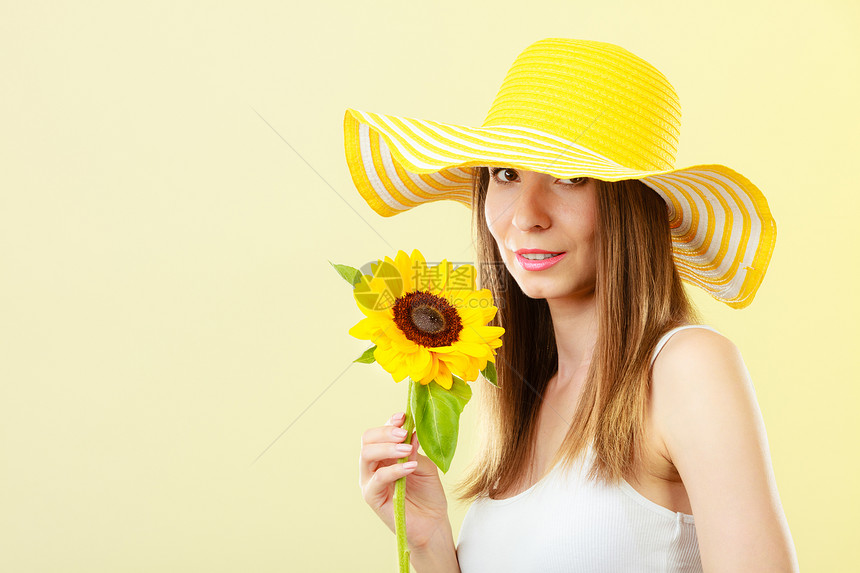 特写吸引人的夏天女人戴着草帽,手里着黄色背景的向日葵图片