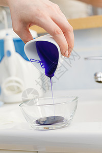 女人把紫色的染发剂洗发水墨粉倒进白色的碗里卫生象妇女倒紫色染发剂洗发水背景图片
