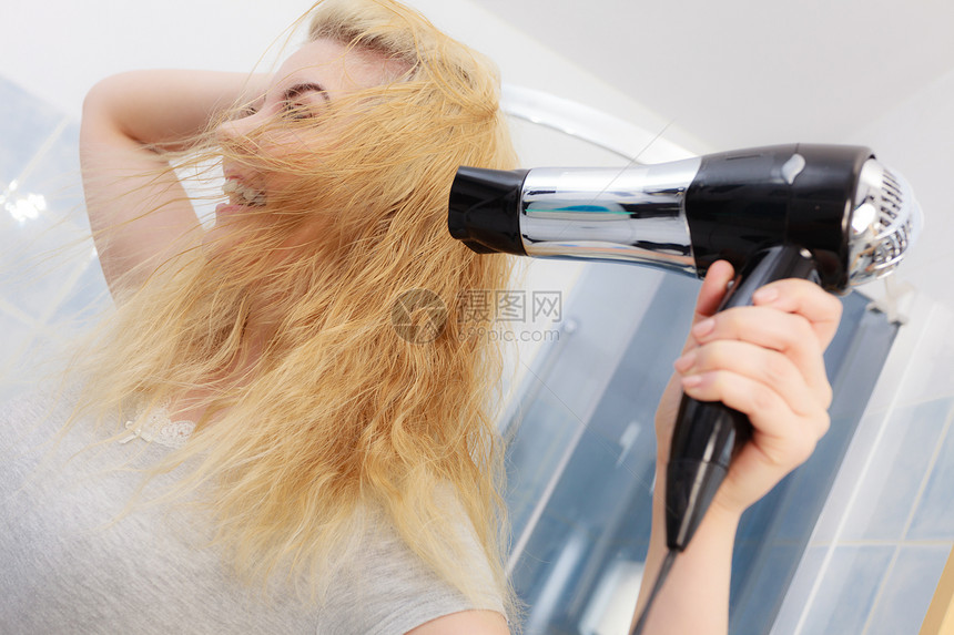 积极的女人她的金发上用风机理发,发型金发女人用风机图片