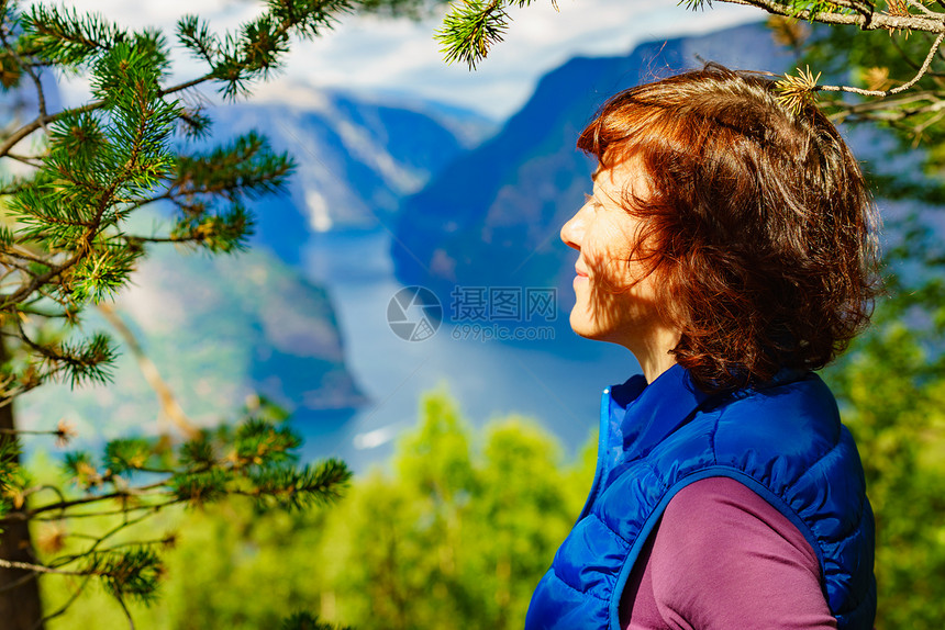 山顶上的游客女人看着挪威峡湾山脉的景色旅游景区路线极光旅行中的假期放松山顶上的游客,挪威图片