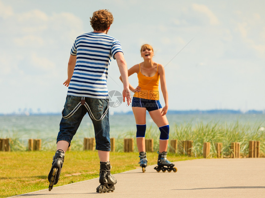 积极的生活方式自由观念轻的适合夫妇骑着溜冰鞋海边户外骑,女人男人享受着时光图片