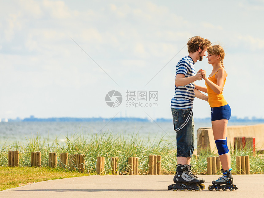 节日,积极的人友谊的轻的穿着溜冰鞋的夫妇骑海边的户外,女人男人长廊上滑行图片