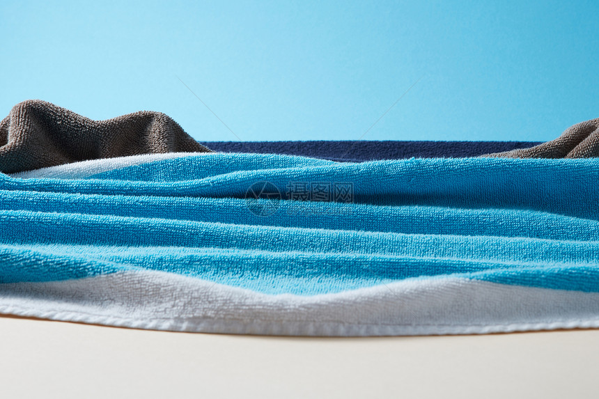 上午夏季海滨手工制作的彩色毛巾双调蓝色米色纸背景与海景与波浪岩石彩色特里毛巾图片
