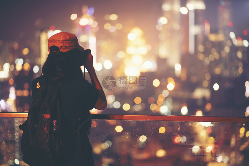 旅行技术轻女子与她的智能手机彼得龙纳斯双胞胎塔吉隆坡晚上拍照图片