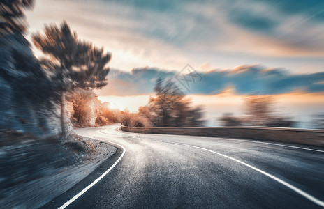 日落时的山路运动模糊的效果沥青路模糊的背景与岩石,蓝天与太阳云夏天快速驾驶美丽的公路运动中运输日背景图片