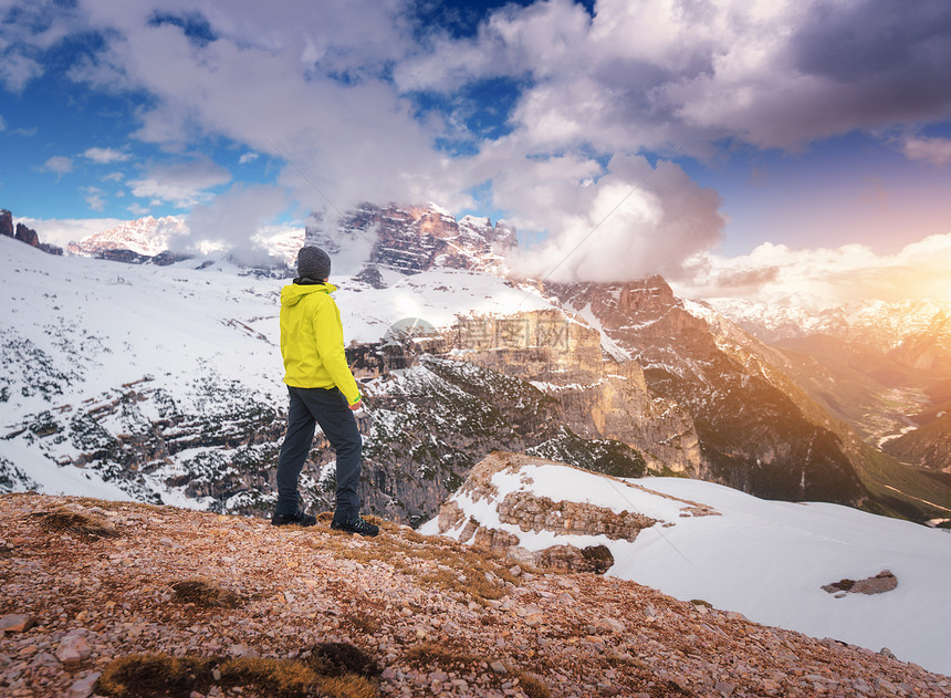 秋天日落时,穿着黄色夹克的轻人山上抗雪山风景与运动的家伙,岩石雪,橙色的草,蓝天与云秋天意大利旅行旅游业图片