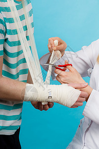 医学医疗保健女医生包扎男手扭伤手腕拜访医学专业人士的轻人医生包扎扭伤了手腕背景图片