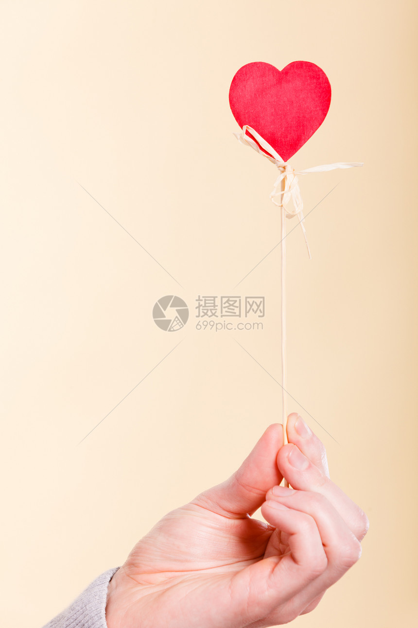 象征爱情浪漫的木棍上的心爱的象征由人的手臂支撑的杆上木棍上的心图片