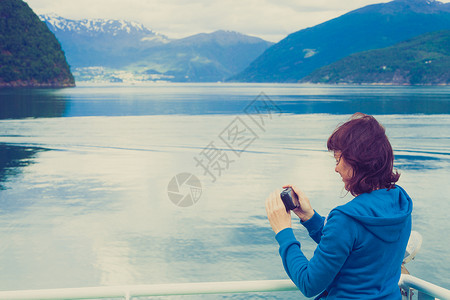 诺德拉达尔斯维格旅游度假旅游游轮上的旅游妇女享受峡湾景观,用相机拍照挪威斯堪的纳维亚欧洲渡船上看的Norddalsfjorde背景