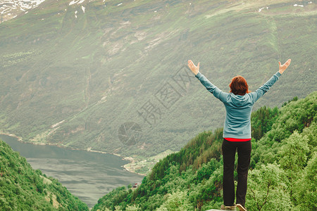 土地税旅行游客妇女欣赏挪威的峡湾美丽的山脉景观挪威山脉峡湾的女游客背景