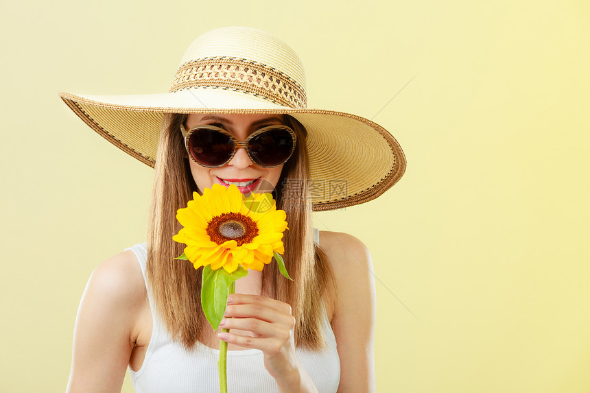特写迷人的夏天女人戴着太阳镜,草帽,手里着黄色背景的向日葵图片