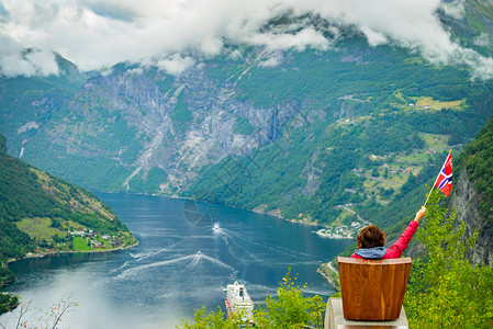 施韦弗利格Flydalsjuvet角度欣赏峡湾Geirangerfjorden风景的女游客,举着挪威巡航度假旅行吉兰格峡背景