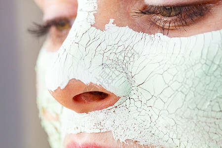 特写女用绿色泥浆具脸上,细节视图十几岁的女孩皮肤上干裂的化妆品美容治疗护肤脸上戴着泥巴具的女孩背景图片