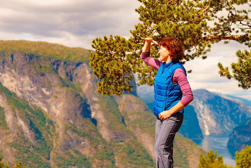 山顶上的游客女人看着挪威峡湾山脉的景色旅游景区路线极光旅行中的假期放松山顶上的游客,挪威图片