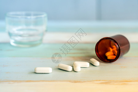 药片药物药瓶中溢出,老式的木制背景上图片