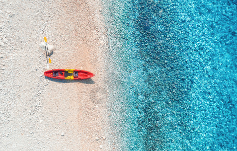 空中观看空沙滩与红色独木舟,海岸与透明的蓝色水阳光明媚的日子背景图片