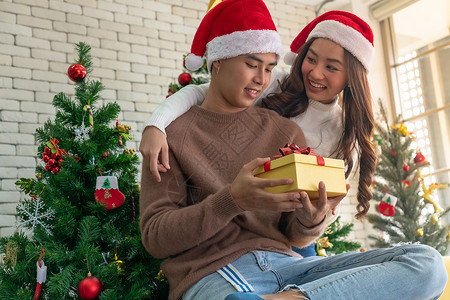 美丽的亚洲女孩圣诞节节日问候时给她的男朋友个惊喜的圣诞礼物图片