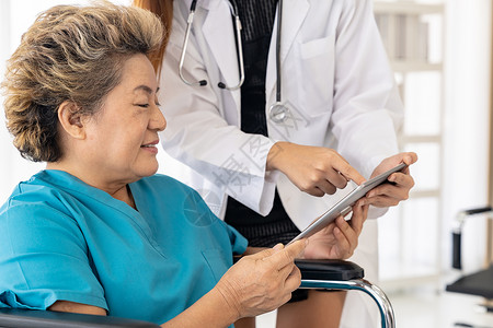 亚洲自信医生用数字平板电脑表达健康关切,老妇女患者坐轮椅上图片