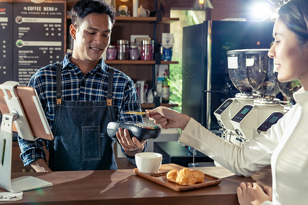 亚洲客户用她的信用卡与非接触式NFS技术支付咖啡师购买咖啡咖啡馆酒吧图片