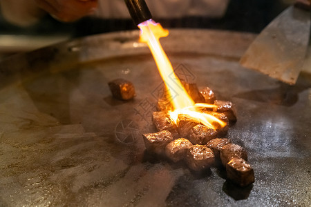 烤牛肉铁板烧食谱日本烤牛肉烹饪锅与刮刀煤气燃烧器火焰图片