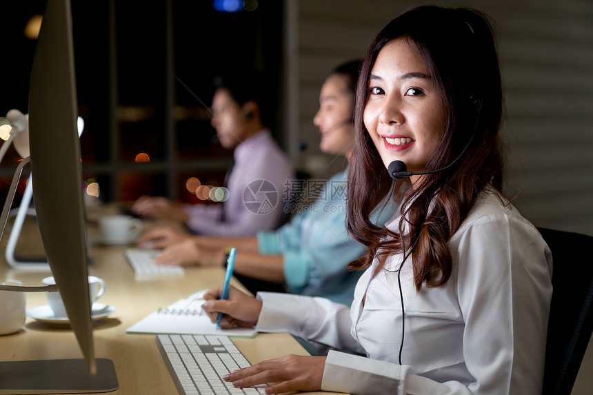 亚洲轻成人信心运营商女代理与耳机工作呼叫中心的夜间环境与他的同事队客户服务技术支持用深夜努力工作24小时图片