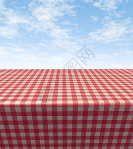在蓝色阳光明媚的夏日天空中带野餐布的桌象征着食物和休闲的乐趣图片