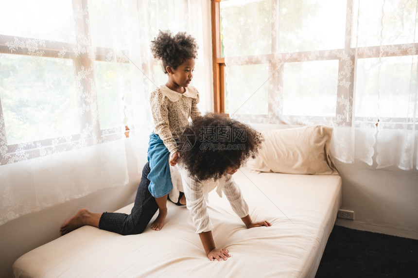 非裔美国儿童在家里的床上玩耍放松图片