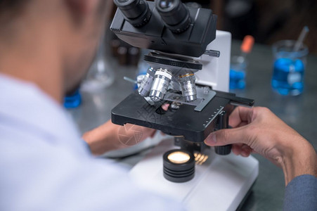 年轻科学家在实验室里通过显微镜观察年轻科学家在做一些研究图片