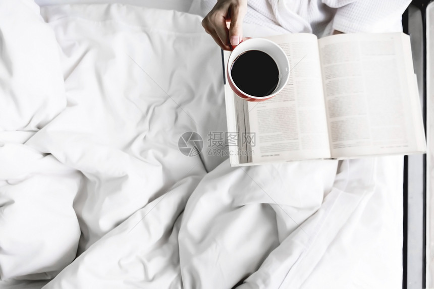 床上女人的柔软照片上面有旧书咖啡和复制空间图片