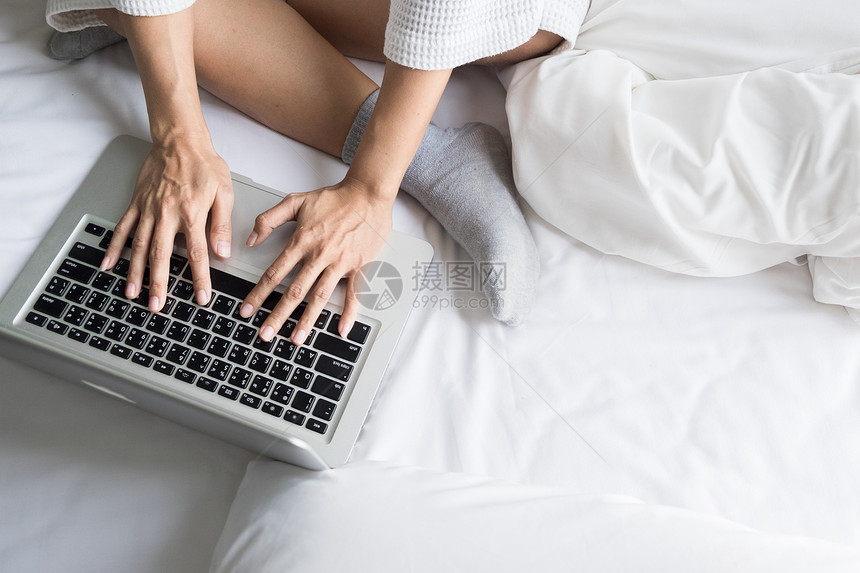 美丽的年轻女士躺在床上家检查笔记本电脑图片