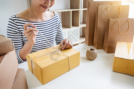 从事网上购物的企业主妇女准备在家中的产品包装过程图片
