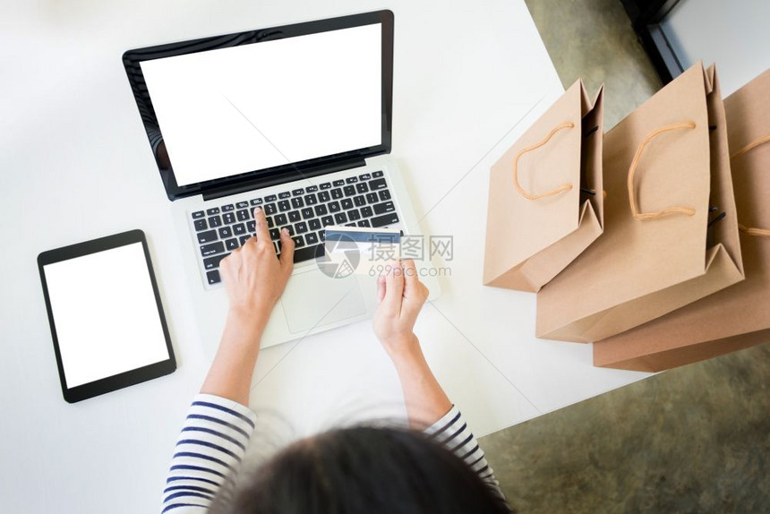 在家使用笔记本电脑时持有信用卡输入息并使用笔记本电脑网上购物概念图片