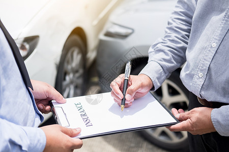 汽车政策在事故后审查车辆索赔时保险代理人在剪贴板上签署保险表将笔寄给他的客户背景