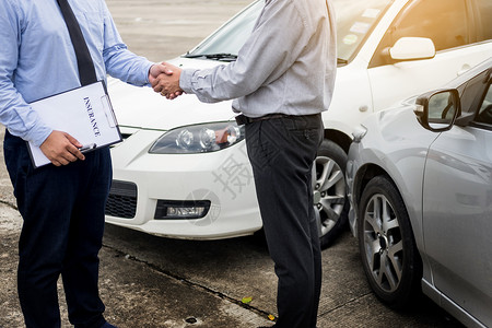客户在同意保险条款后与汽车保险代理人握手图片