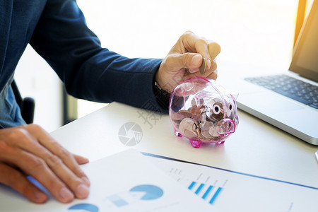 卡通小猪商人把硬币放进小猪银行储蓄和投资的概念背景