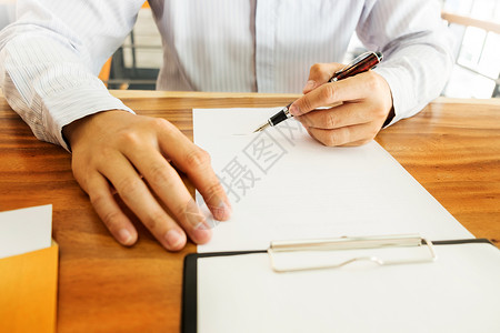 商人在办公桌上用笔签署合同图片