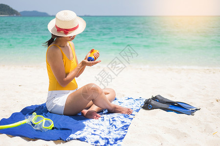 在沙滩上的年轻女孩在用防晒霜背景图片