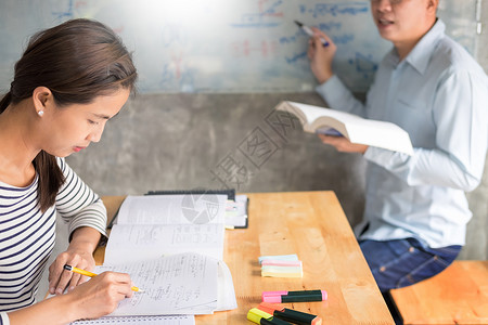 妇女学习并教女师概念育互相帮助坐在教室的桌椅上背景图片